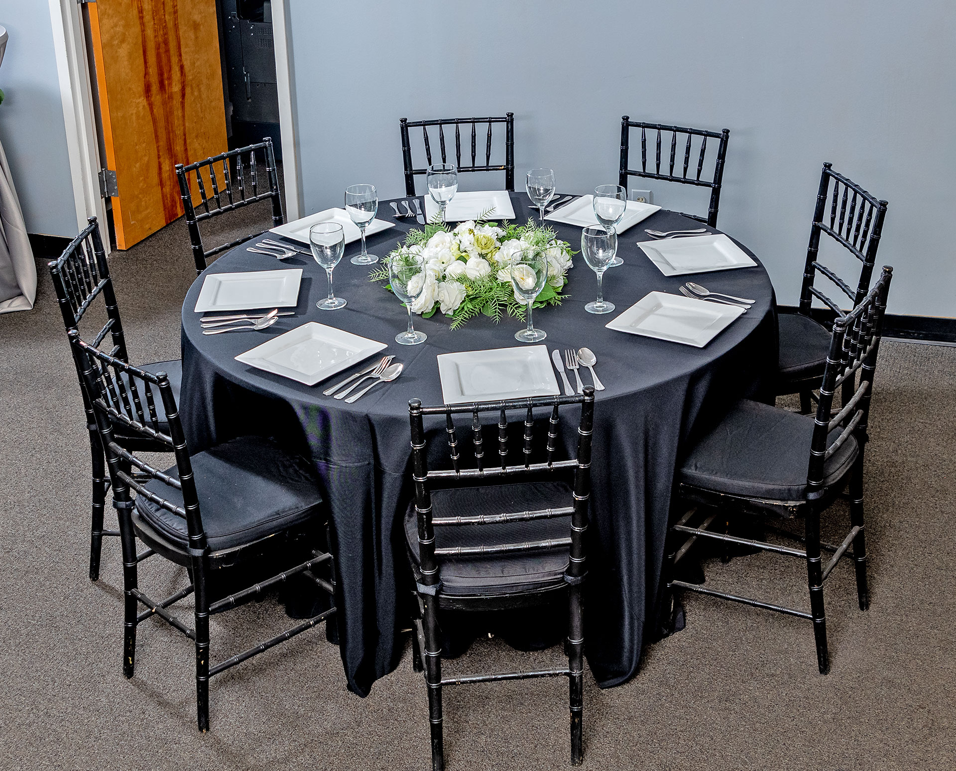 Black Chiavari Chairs around a Round Table with Black Tablecloth and White Square Plates